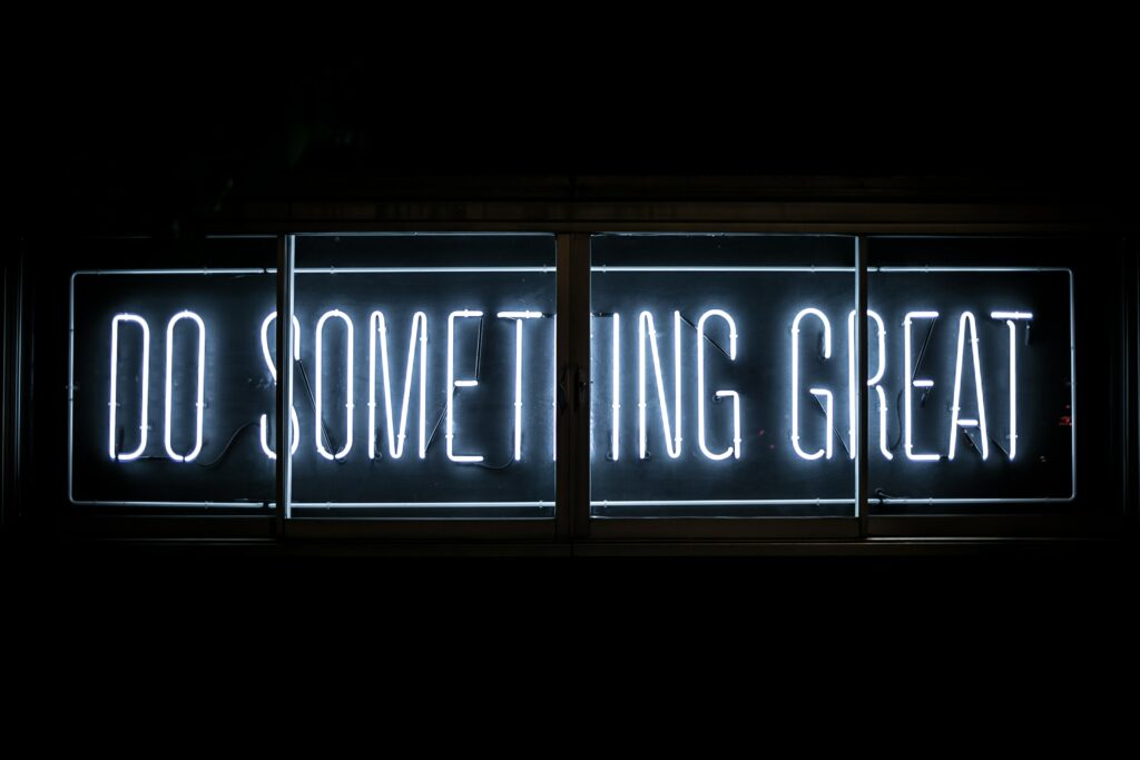 Neonschriftzug "Do something great" auf schwarzem Hintergrund - Werbung für Freiwilligendienste (Photo by Clark Tibbs on Unsplash)